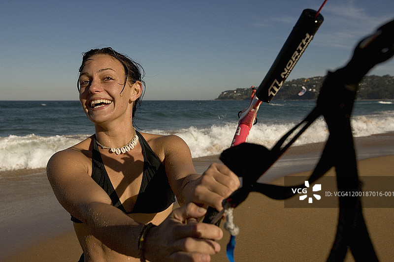 在海滩上双手抓住绳索的女性风筝冲浪者图片素材