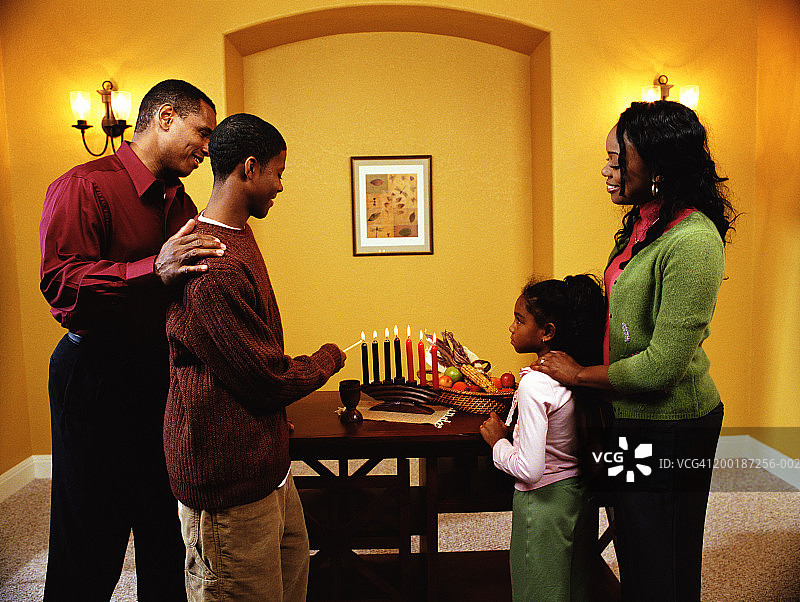 青少年男孩（12-14岁）与家人一起点燃宽扎节蜡烛，侧视图图片素材