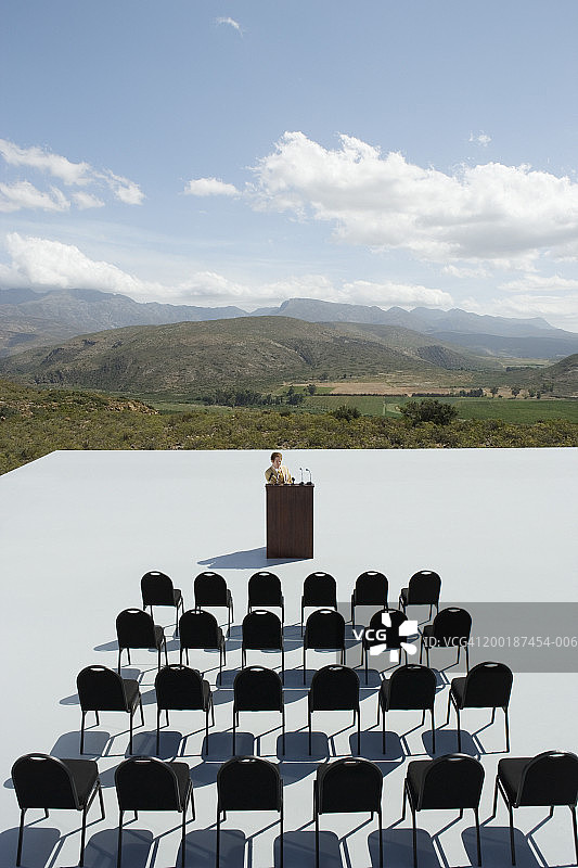 男子在户外平台上空椅子前发表演讲图片素材