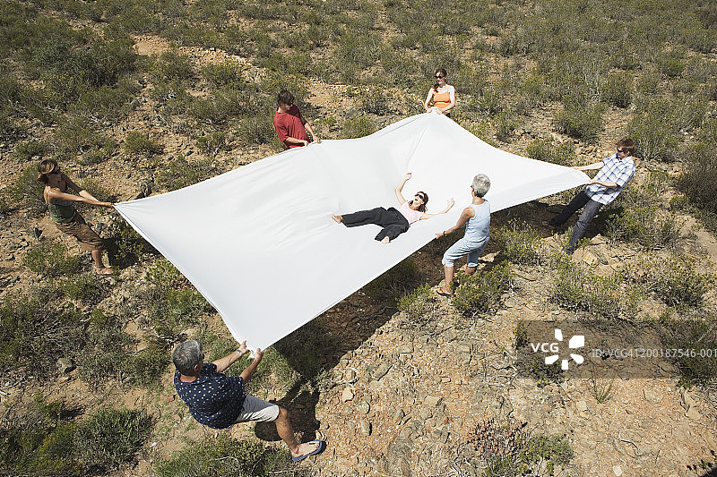 户外：一群人用大床单接住一位女士图片素材