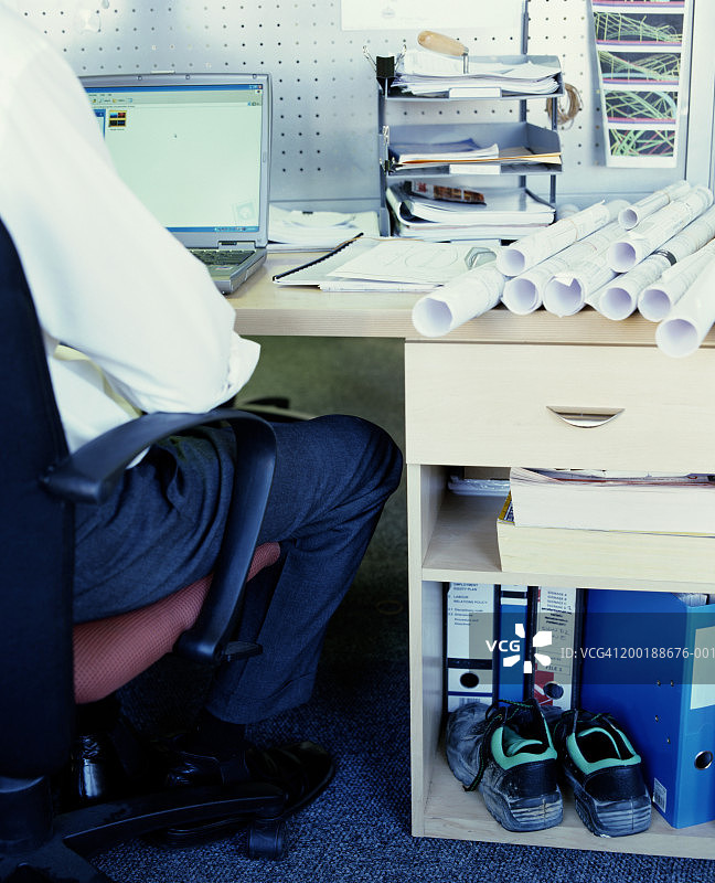 男人坐在桌旁使用笔记本电脑后视图图片素材