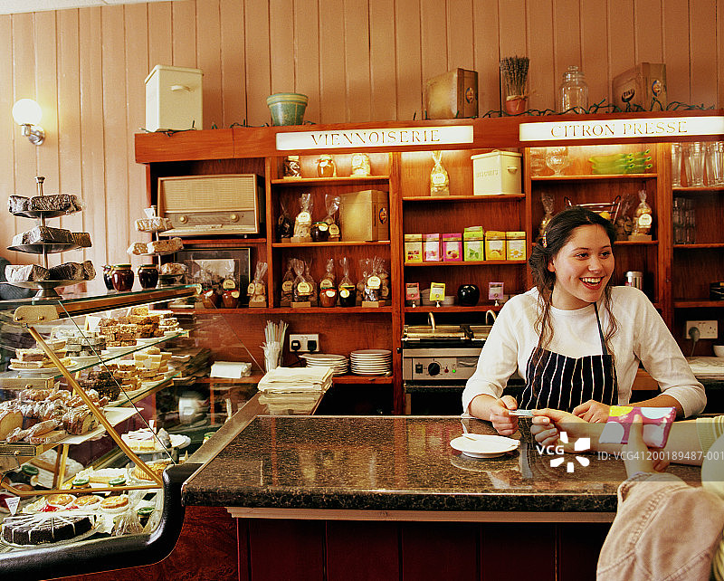 少女在咖啡馆柜台后微笑收款图片素材
