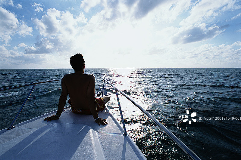 坐在船头眺望大海的男人，后视图图片素材