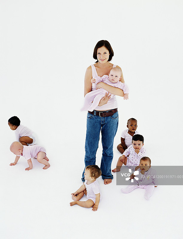 一群（7-12个月）的婴儿围绕着女人，微笑，肖像图片素材
