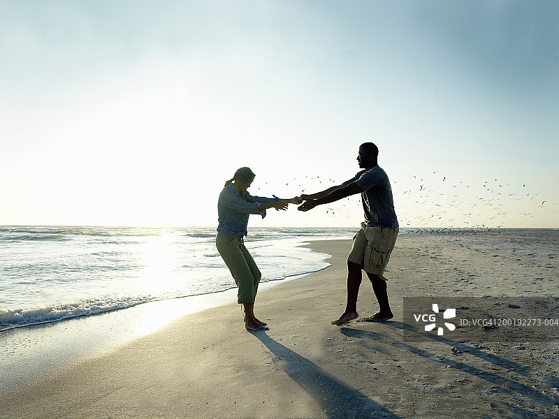 年轻情侣在海滩上牵手嬉戏图片素材