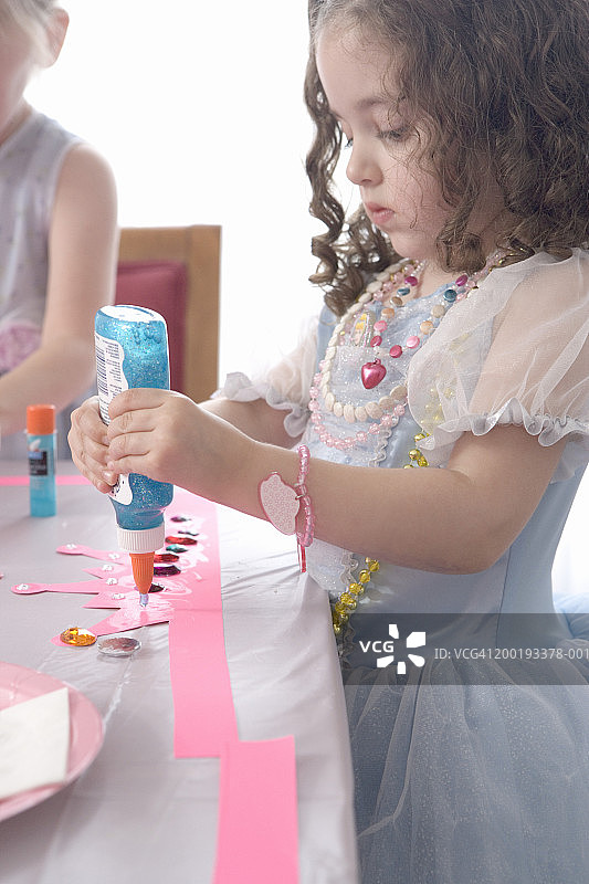 在茶话会上制作公主皇冠的3-5岁小女孩侧视图图片素材