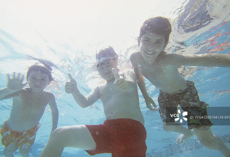 三个微笑的男孩(6-12岁)在水下，肖像图片素材