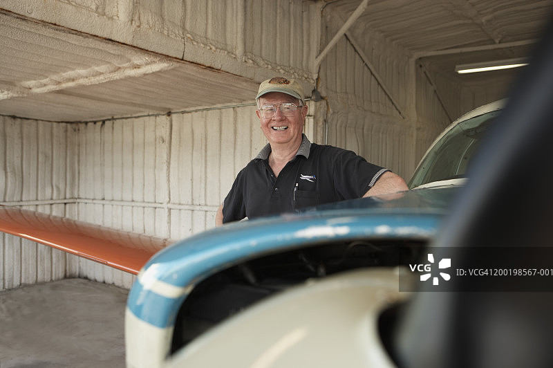 年长的男人站在飞机旁，微笑，肖像图片素材