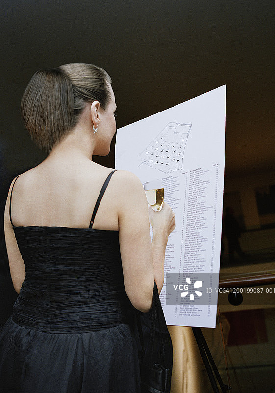 女人看着座位表，拿着饮料，后视图图片素材