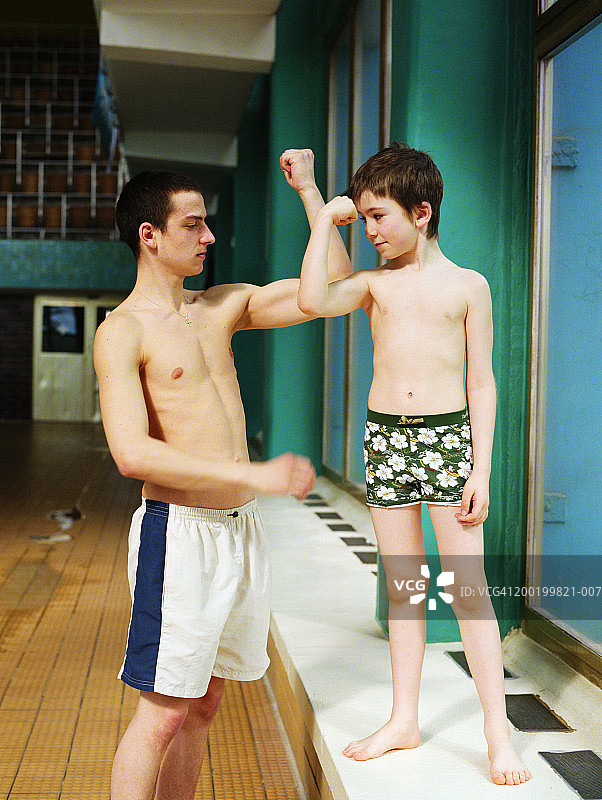 年轻男人和男孩(7-9岁)比较肱二头肌图片素材