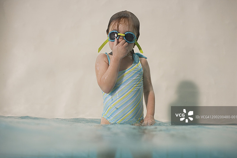 戴着护目镜捂着鼻子站在游泳池里的小女孩（3-5岁）图片素材