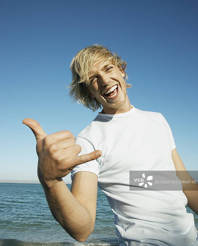 海边的年轻男子做着手势，笑着，肖像图片素材