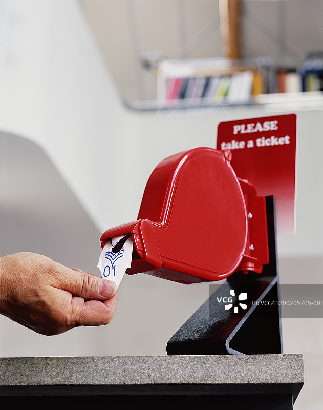 男人从取号机取出第一张票，特写图片素材