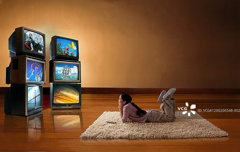 女孩（10-12岁）躺在地板上看电视屏幕图片素材