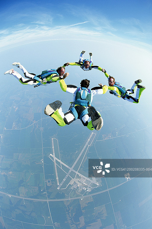 四个男性跳伞运动员手拉手编队飞行鸟瞰图图片素材