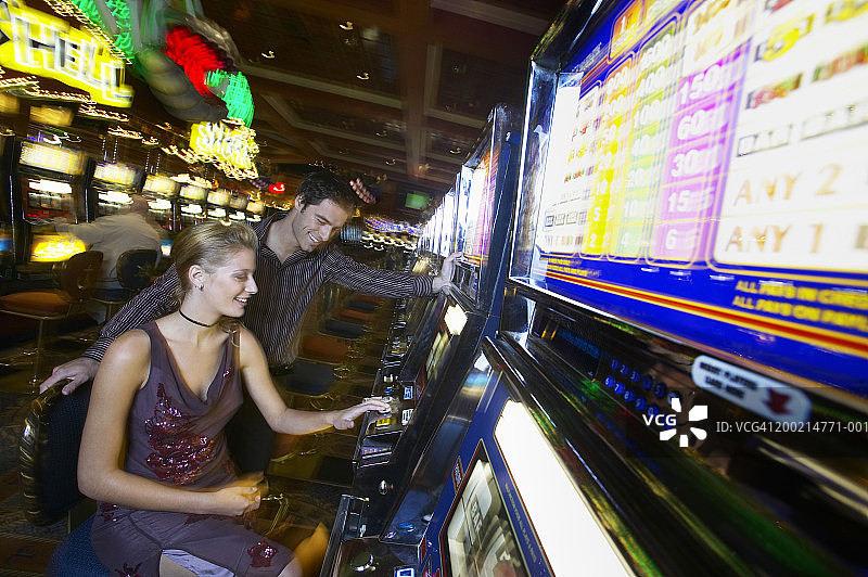 年轻男人看年轻女人玩赌场水果机图片素材