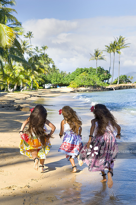 三个（8-10岁）的女孩在海滩上奔跑，后视图图片素材