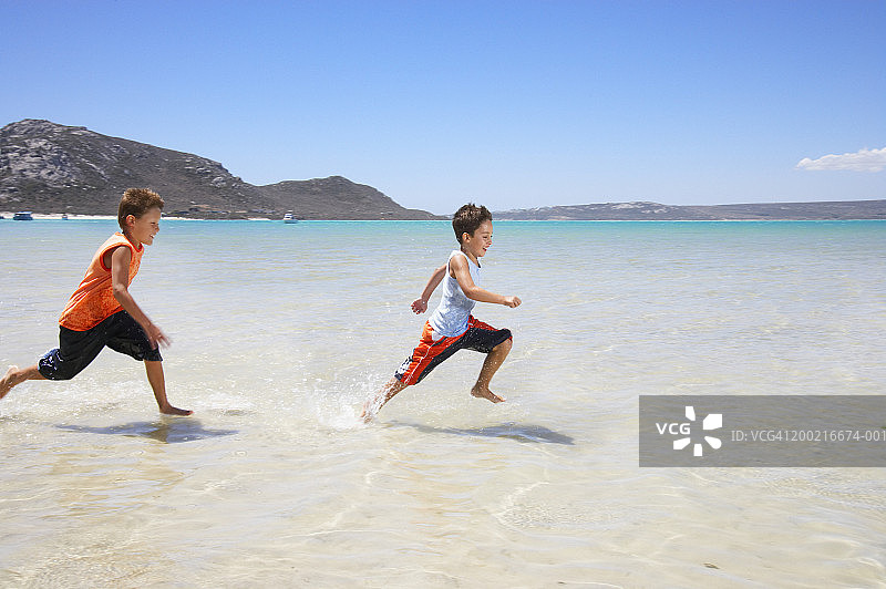 两个男孩（7-9岁）在海里奔跑，微笑，侧视图图片素材