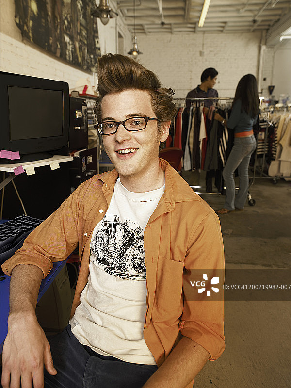 服装厂办公桌前微笑的年轻人肖像图片素材
