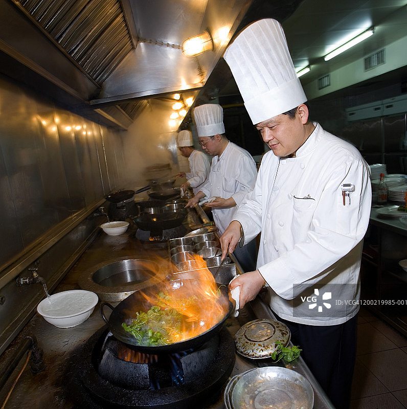 三位厨师在餐厅厨房做饭，准备炒菜图片素材