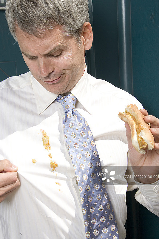 在户外，热狗酱洒在衬衫上的商人特写图片素材