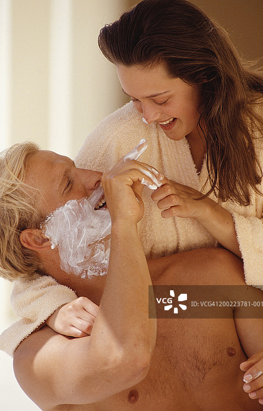 年轻女子拥抱脸上涂着剃须泡沫的男人图片素材
