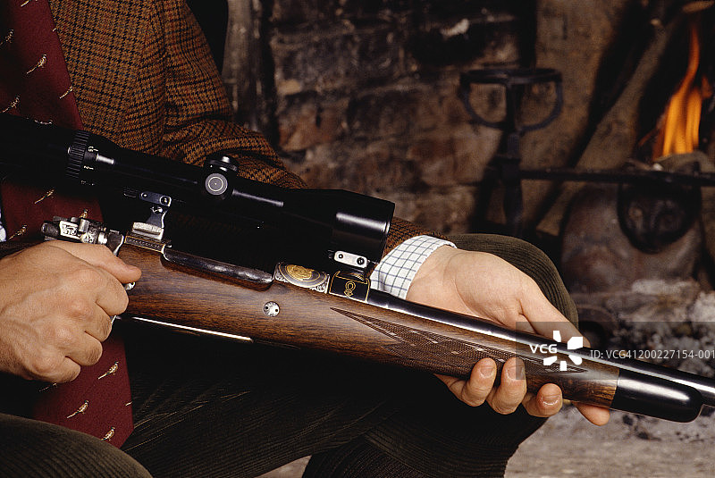 男人坐在壁炉旁手持步枪图片素材