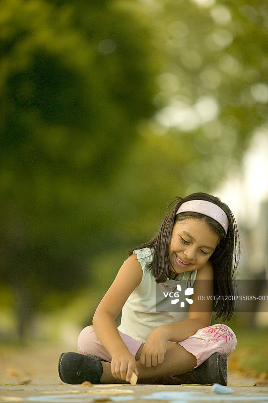 在人行道上用粉笔画画的女孩（5-7岁），微笑图片素材