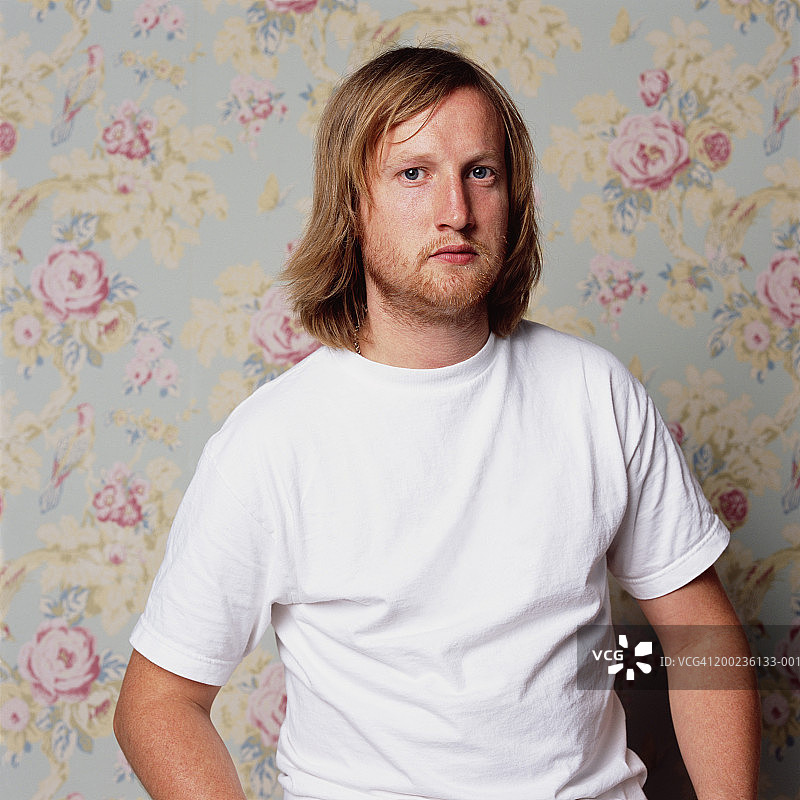 身穿白色T恤，站在花纹墙前的男人肖像图片素材
