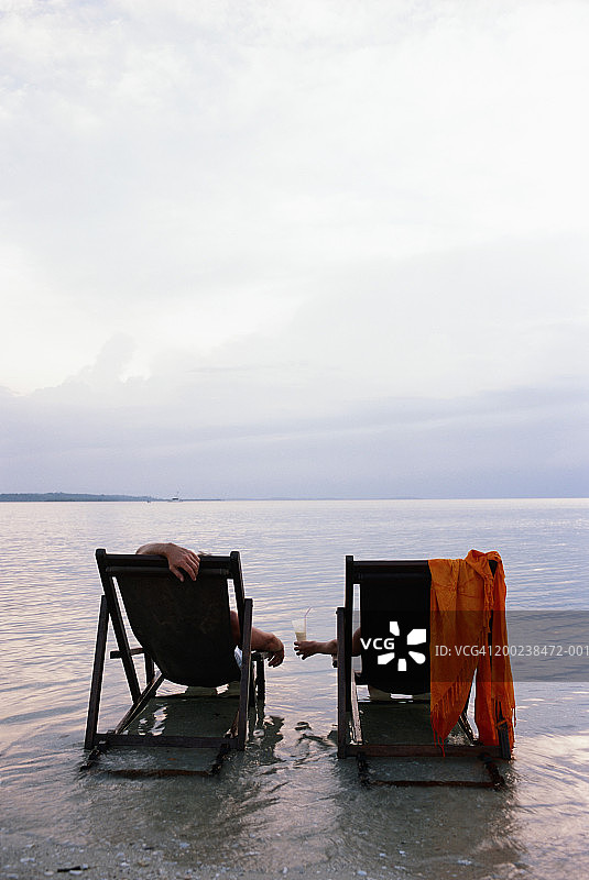 情侣在水中躺椅上放松（后视图）图片素材