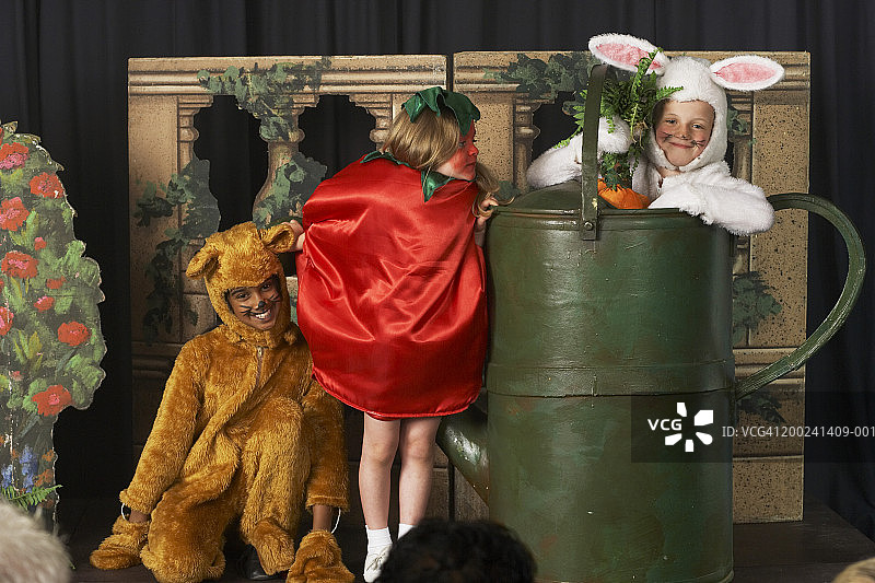 三个穿着食物和动物服装的孩子在舞台上表演图片素材