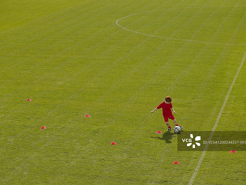 男孩（7-9岁）在足球场上绕着训练锥运球图片素材