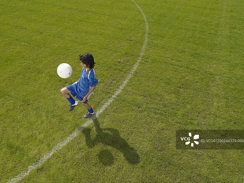 男孩(8-10岁)练习足球技巧，高角度拍摄图片素材