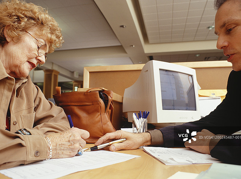 金融顾问协助女士处理文件侧视图图片素材