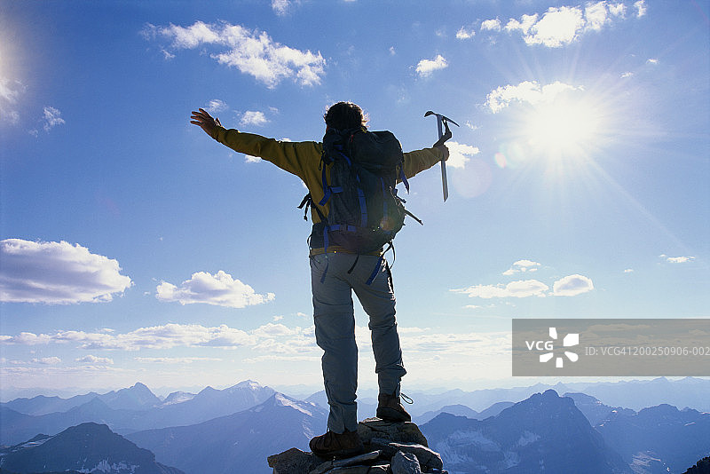 在山上举起双臂的男人，后视图图片素材