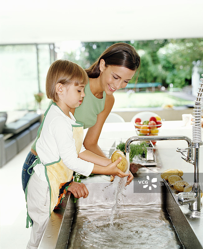 母女（3-5岁）在厨房水槽洗土豆的侧视图图片素材