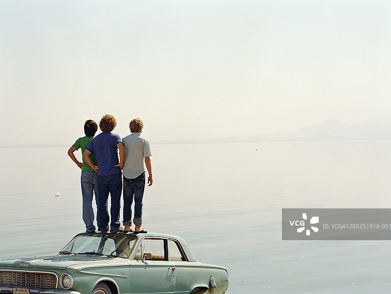 青年男子站在水中的车顶上（后视图）图片素材