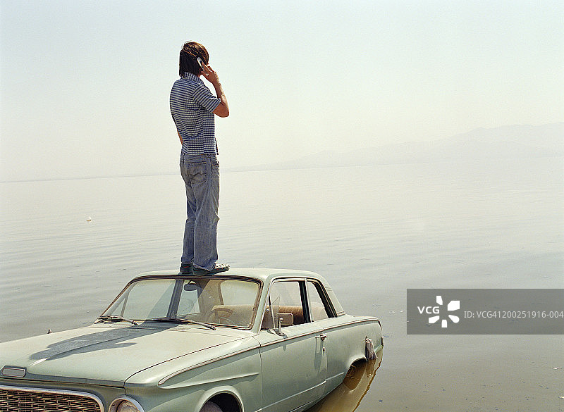 站在水里汽车顶上的年轻男人图片素材
