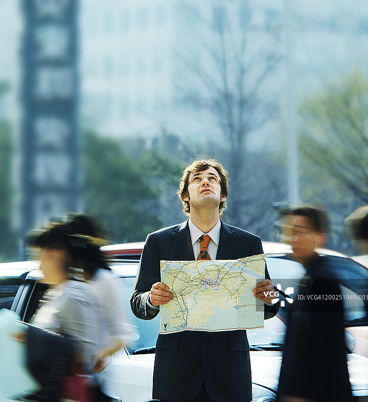 在户外拿着地图向上看的商人图片素材
