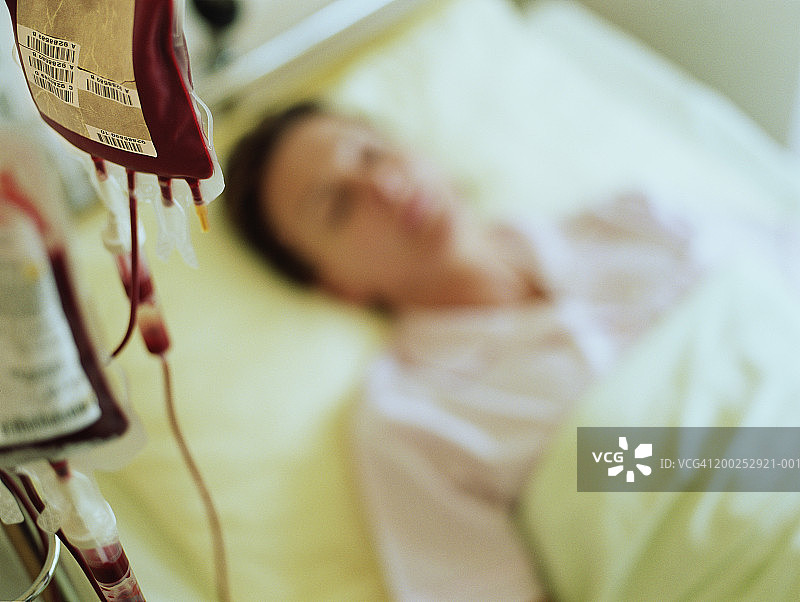 在医院病床上接受静脉滴注的女人（焦点在滴注上）图片素材
