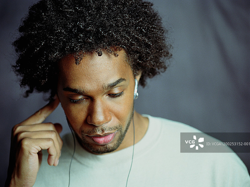 戴着耳机的年轻男人向下看图片素材