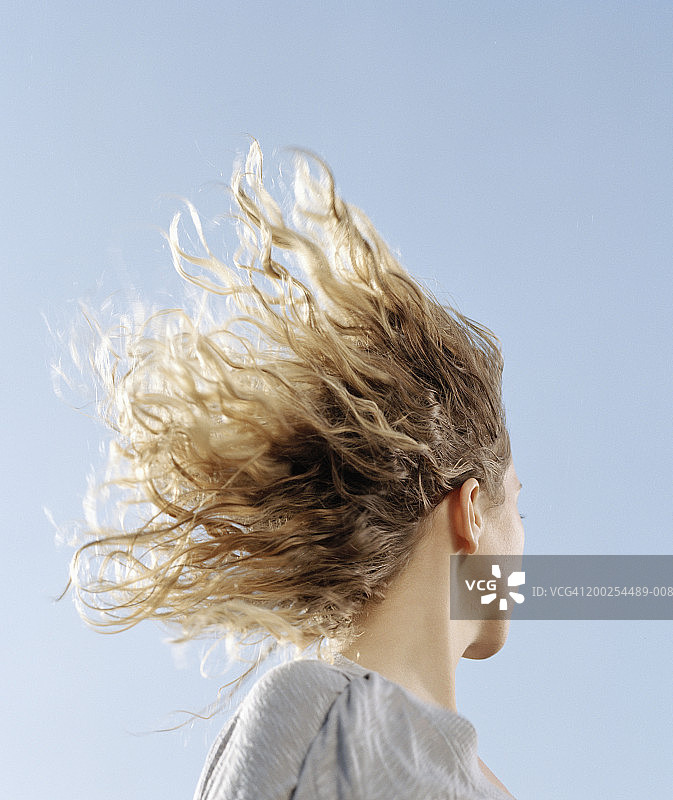 头发在风中飘扬的年轻女人侧面特写图片素材