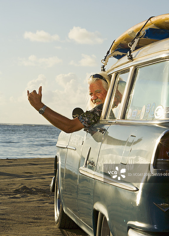 中年男人在车里车顶放冲浪板做手势图片素材