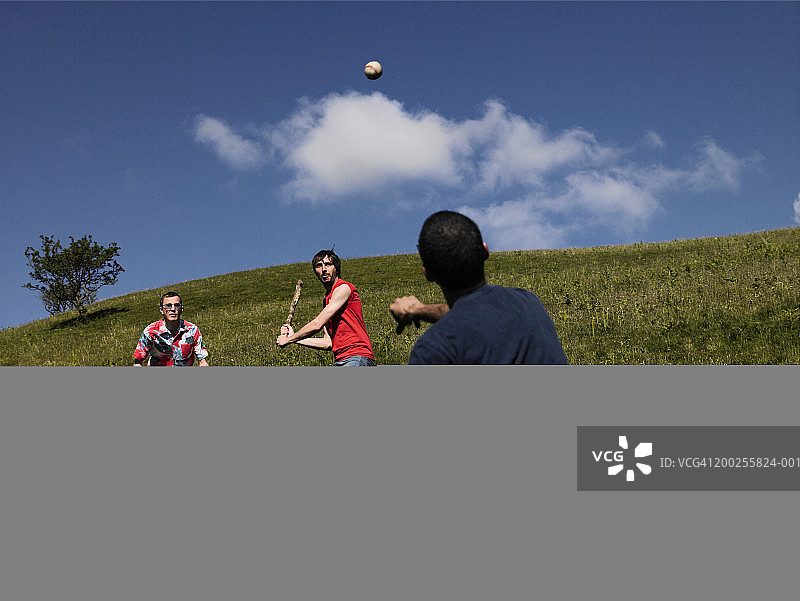 三个男人用棍子打棒球图片素材