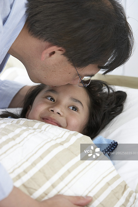 躺在床上，父亲亲吻额头的女孩（4-6岁）图片素材