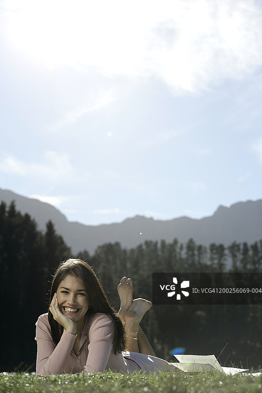 年轻女人在草地上看书微笑图片素材
