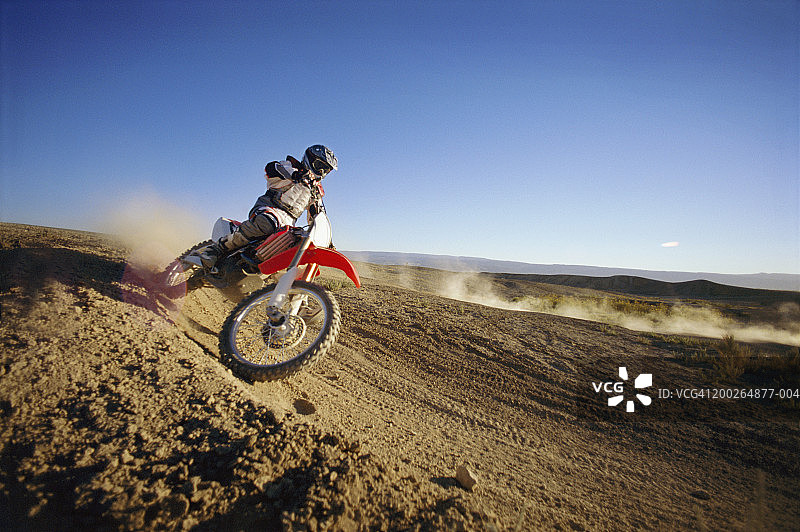 越野摩托车手在土路上，侧视图图片素材