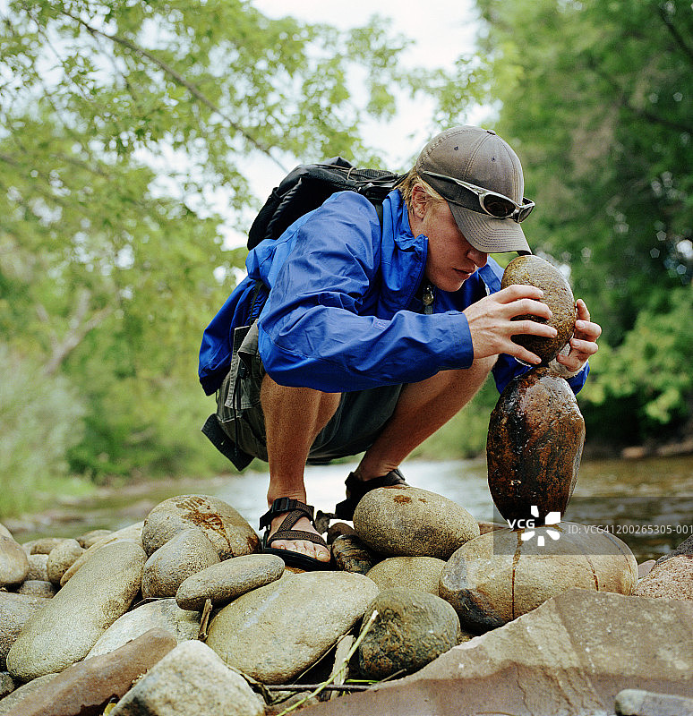 男人在溪流附近堆叠石头侧视图图片素材