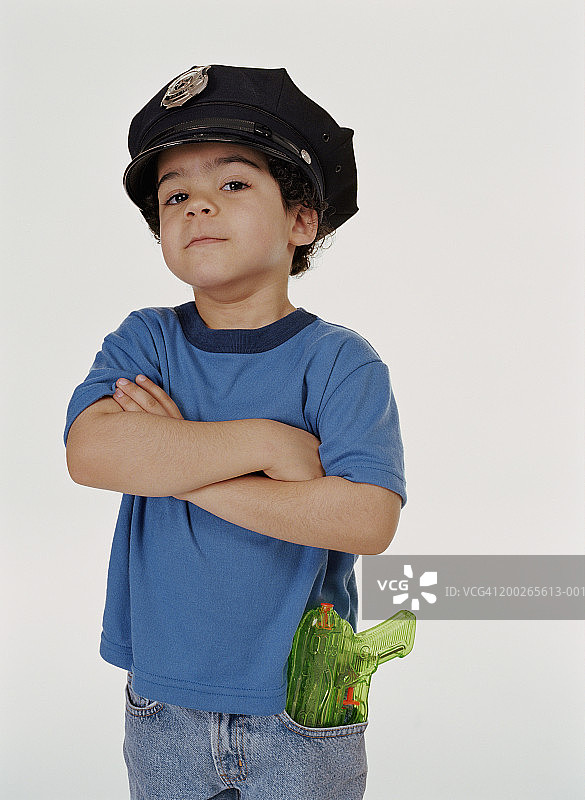 戴着警察帽、手臂交叉的男孩肖像（4-6岁）图片素材
