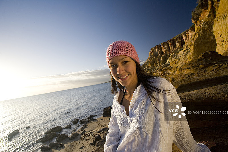 在海滩岩石上微笑的少女（15-17岁），人像图片素材
